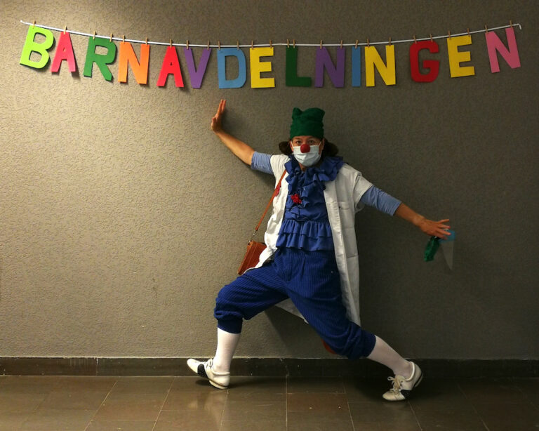 Clownen Jonas står under en banderoll med ordet 